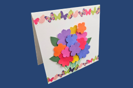 A handmade card decorated with a colorful bouquet of flowers and a border of butterflies.